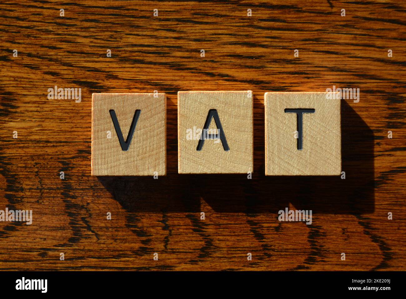 VAT, Akronym für Value Added Tax in hölzernen Buchstaben isoliert auf texturiertem Holzhintergrund Stockfoto
