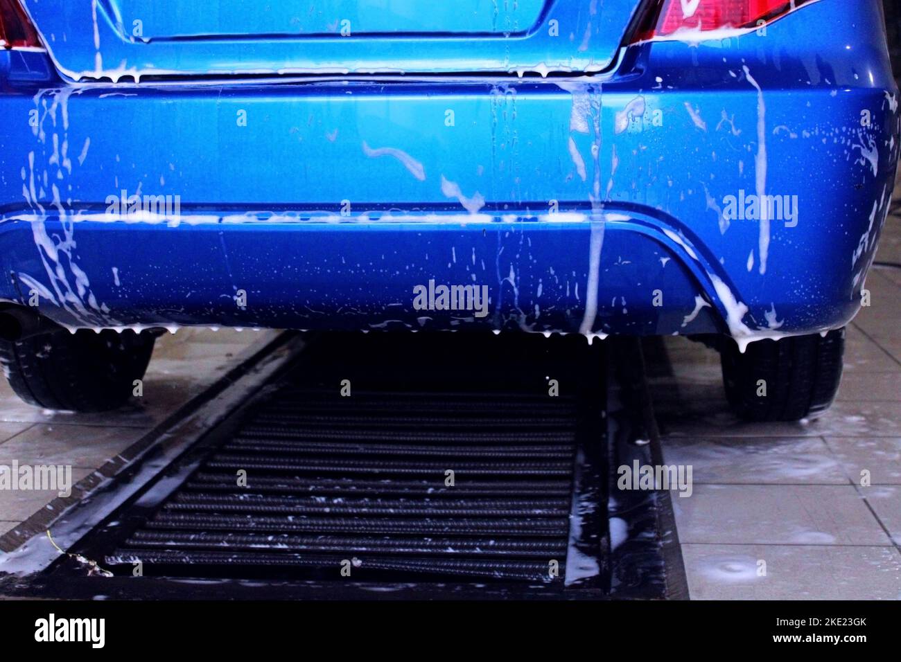 Die Rückseite eines blauen Autos in Nahaufnahme bei einer Waschanlage. Das Konzept der Ökologie und Umweltverschmutzung. Stockfoto