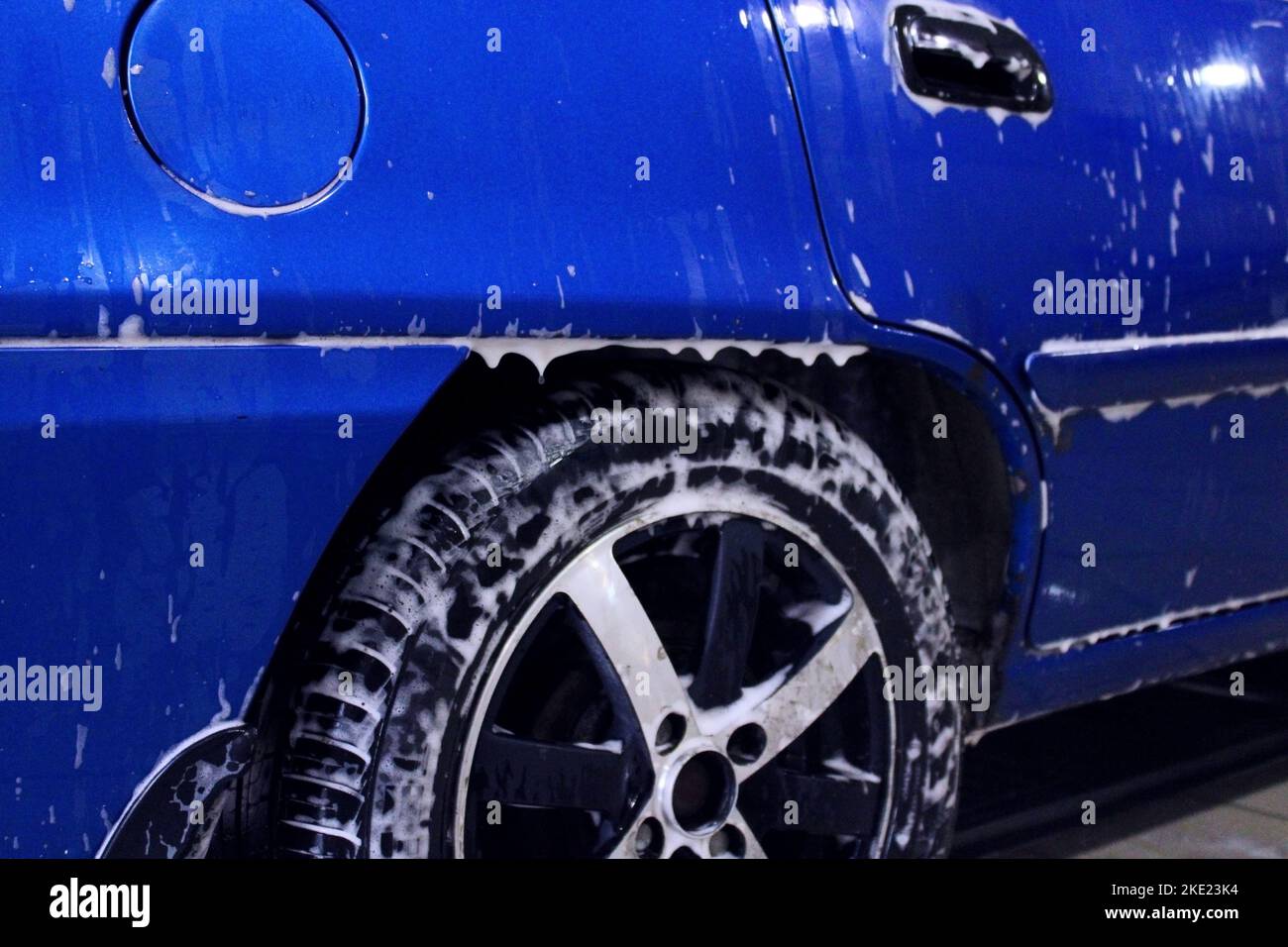 Die Rückseite eines blauen Autos in Nahaufnahme bei einer Autowäsche. Seitenansicht. Das Konzept der Ökologie und Umweltverschmutzung. Stockfoto