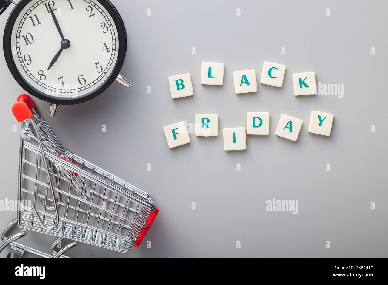Schwarzer freitagstext, Wecker und Warenkorb auf grauem Hintergrund. Draufsicht. Stockfoto