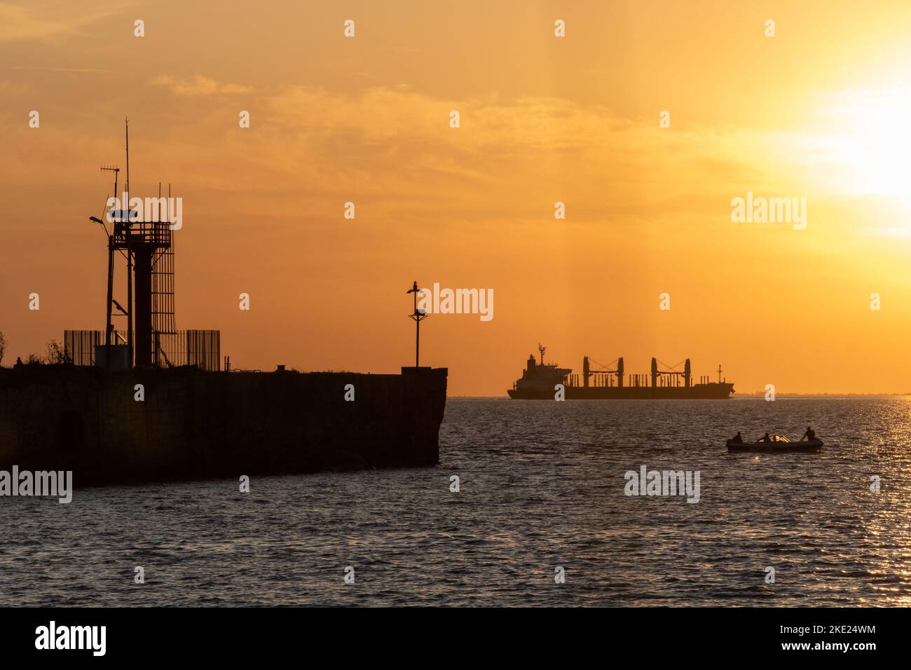 Ein großes Frachtschiff, ein kleines Boot und eine alte Anlegestelle sind am Uruguay River, Conchillas, Uruguay zu sehen Stockfoto