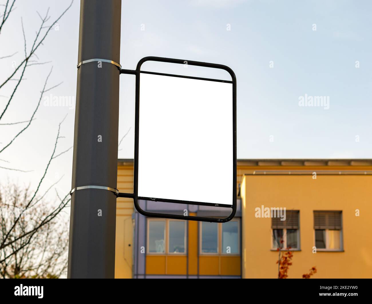 Vorlage für eine Werbung auf einem Lichtpfosten. Leerer weißer Bereich zum Testen eines Posterdesigns. Marketing in einem öffentlichen Bereich mit einem Gebäude dahinter. Stockfoto