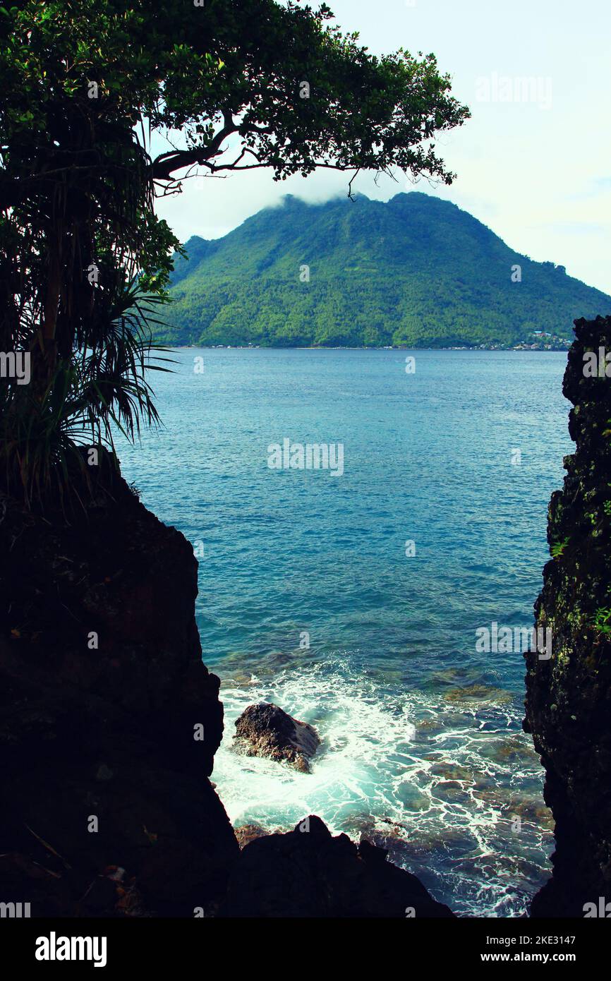 Die Insel HIRI im Norden Malukus ist in der Entfernung zwischen den Felsen vor dem blauen Meer als Hintergrund zu sehen. Stockfoto