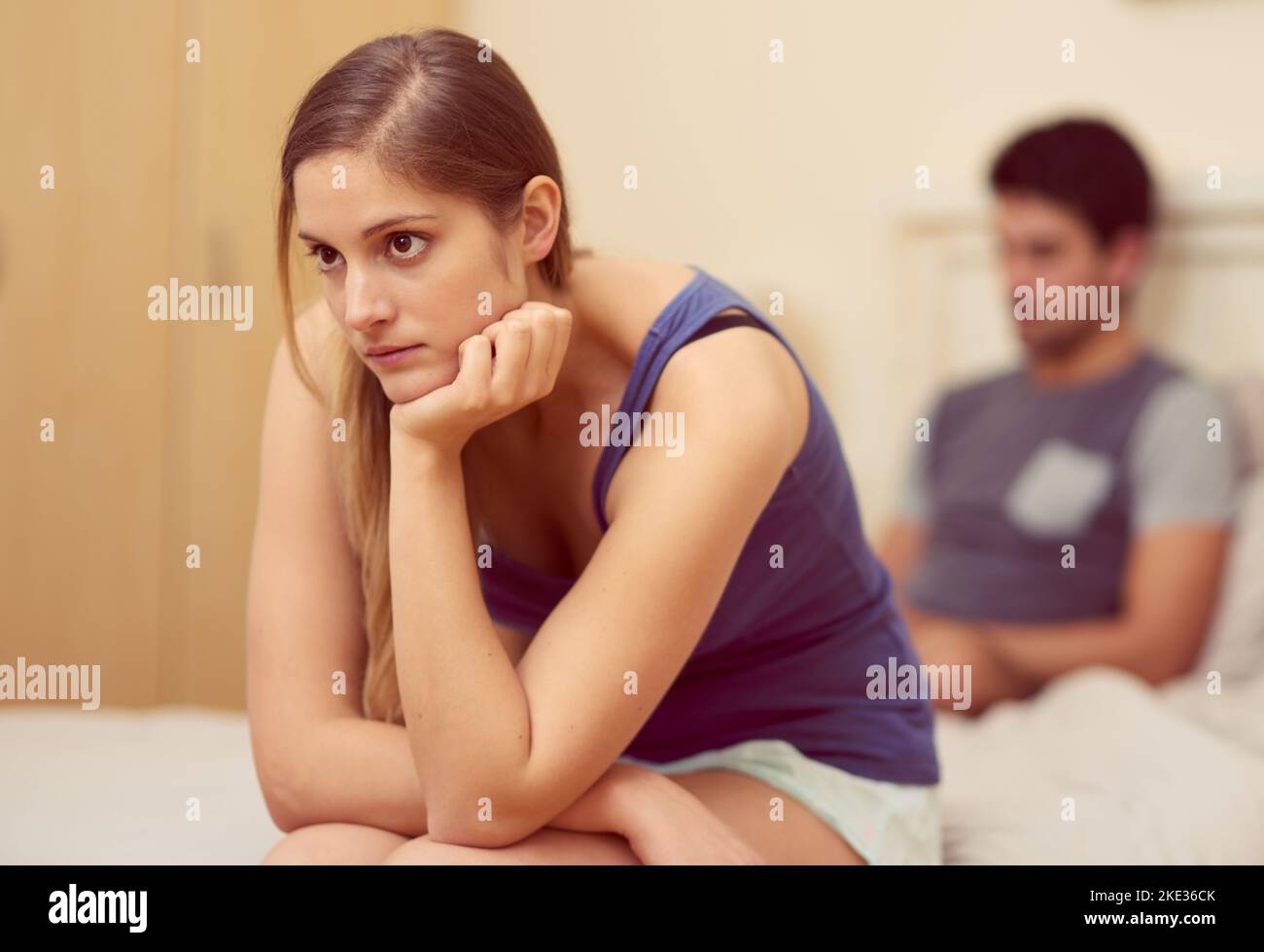 Wie bringen wir diese Beziehung wieder auf Kurs? Eine unglückliche junge Frau, die auf dem Bett sitzt, nachdem sie mit ihrem Freund gekämpft hat. Stockfoto