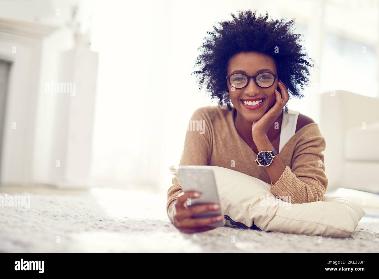 Es ist meine Verbindung nach außen von innen. Eine junge Frau, die ihr Telefon zu Hause benutzt. Stockfoto