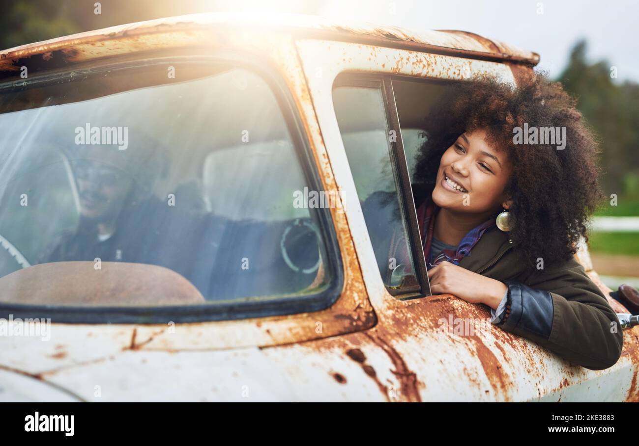 Eine glückliche junge Frau, die in einem rostigen alten Lastwagen sitzt. Stockfoto
