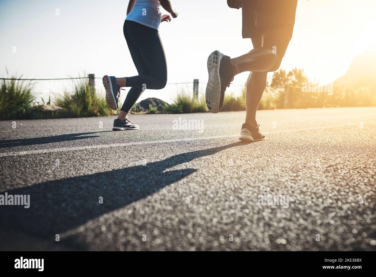 Es gibt keine Ziellinie. Zwei unkenntliche Menschen laufen auf einer asphaltierten Straße. Stockfoto