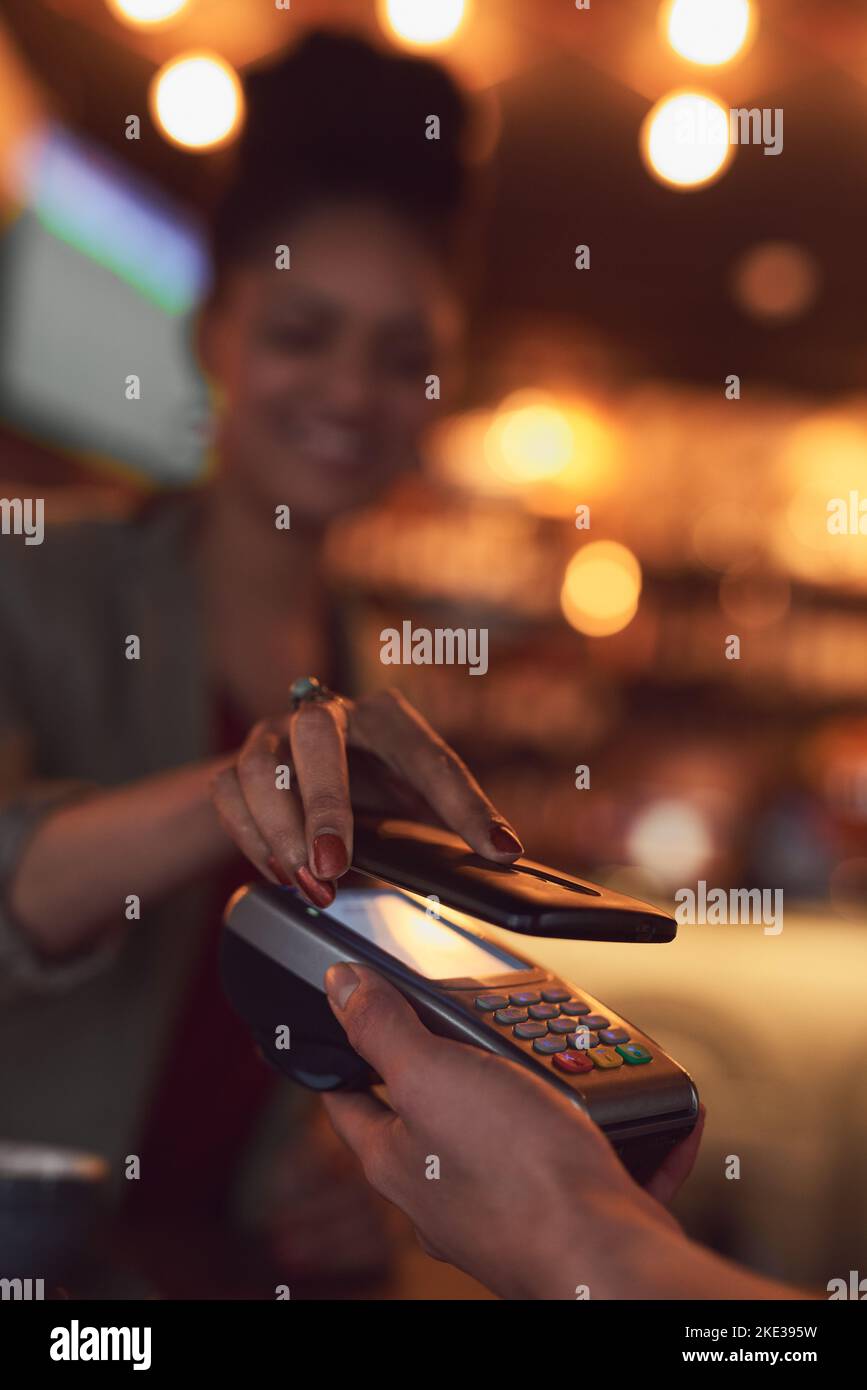 Sie müssen nie wieder Bargeld mit sich führen. Nahaufnahme einer Frau, die mit NFC-Technologie in einem Café bezahlt. Stockfoto