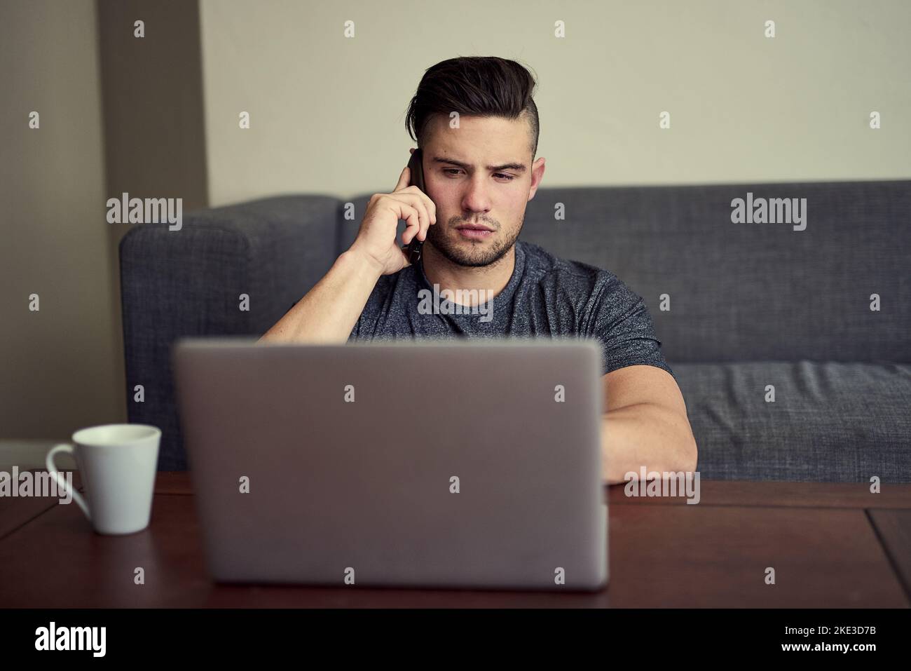 Haben Sie meine E-Mail noch erhalten? Ein fahrender junger Mann, der während der Arbeit von seiner Lounge zu Hause aus sein Telefon beantwortet. Stockfoto