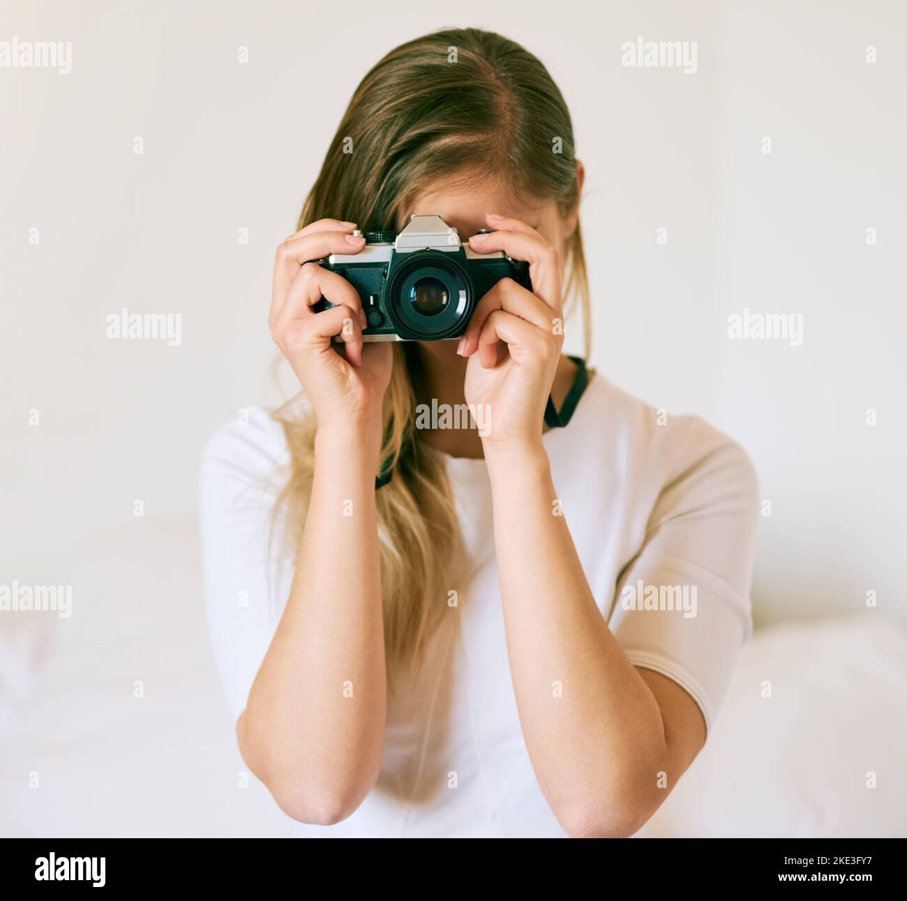 Sagen Sie Käse. Eine nicht erkennbare junge Frau, die zu Hause mit ihrer Kamera ein Foto gemacht hat. Stockfoto Sagen Sie Käse. Eine nicht erkennbare junge Frau, die zu Hause mit ihrer Kamera ein Foto gemacht hat. Stockfoto