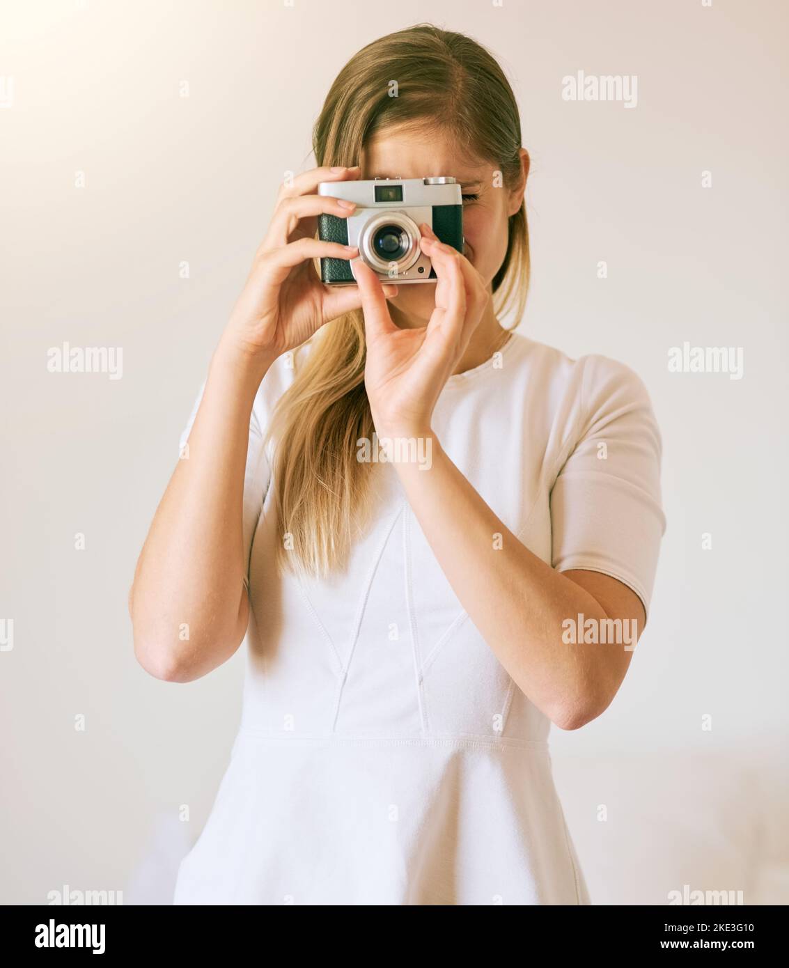 Aufnahme der Welt ein Bild nach dem anderen. Eine nicht erkennbare junge Frau, die zu Hause mit ihrer Kamera ein Foto gemacht hat. Stockfoto Aufnahme der Welt ein Bild nach dem anderen. Eine nicht erkennbare junge Frau, die zu Hause mit ihrer Kamera ein Foto gemacht hat. Stockfoto