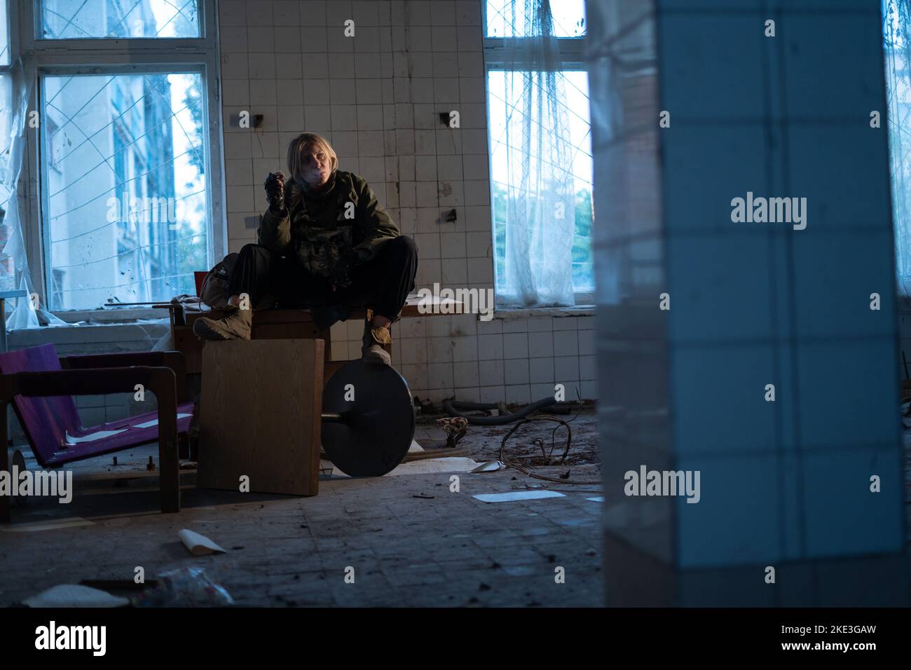 Post-Apokalypse. Eine junge Frau sitzt und raucht in einem verlassenen Gebäude. Konzept eines Mannes, der in einer post-apokalyptischen Welt auf der Suche nach Nahrung wandert. Stockfoto