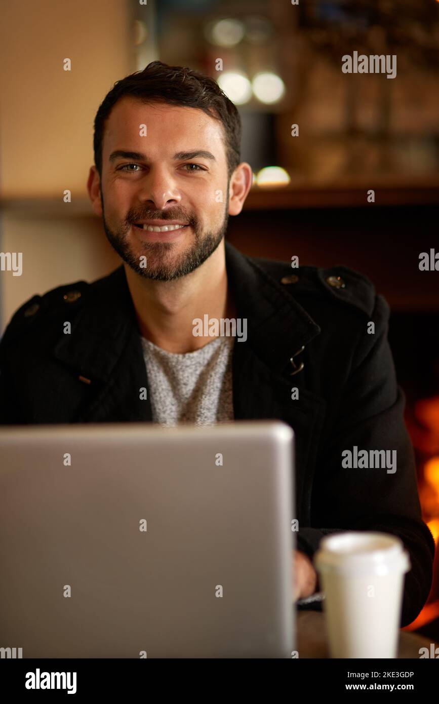 Für einen produktiven Tag fügen Sie einfach Kaffee und WLAN hinzu. Porträt eines hübschen jungen Mannes, der in einem Café im Internet surft. Stockfoto