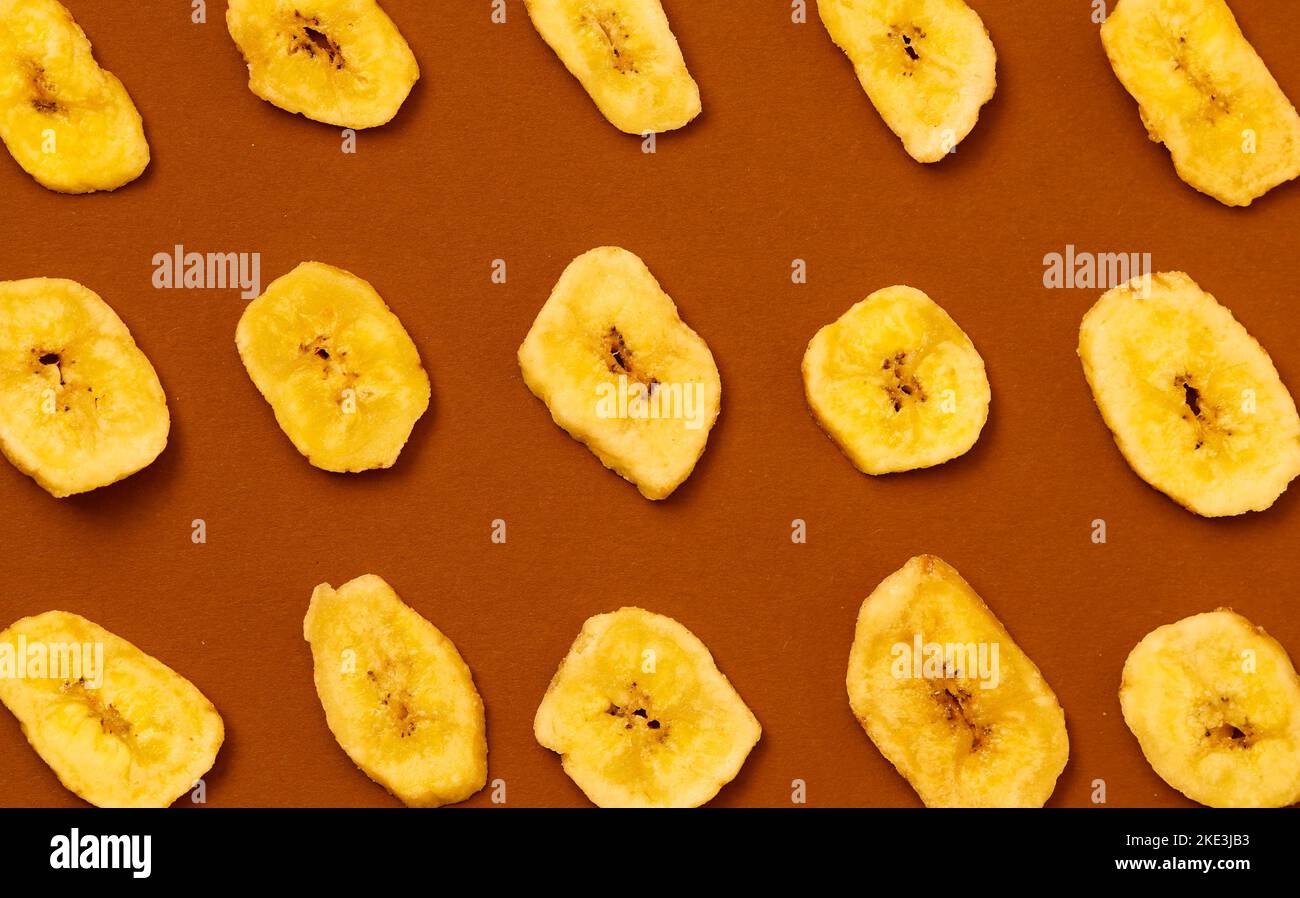 Gelbe Bananenchips auf braunem Hintergrund. Stockfoto
