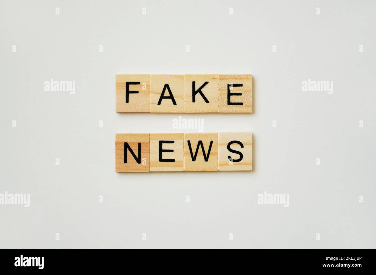 Fake News. Schwarzer Schriftzug auf Holztellern. Weißer Hintergrund. Stockfoto