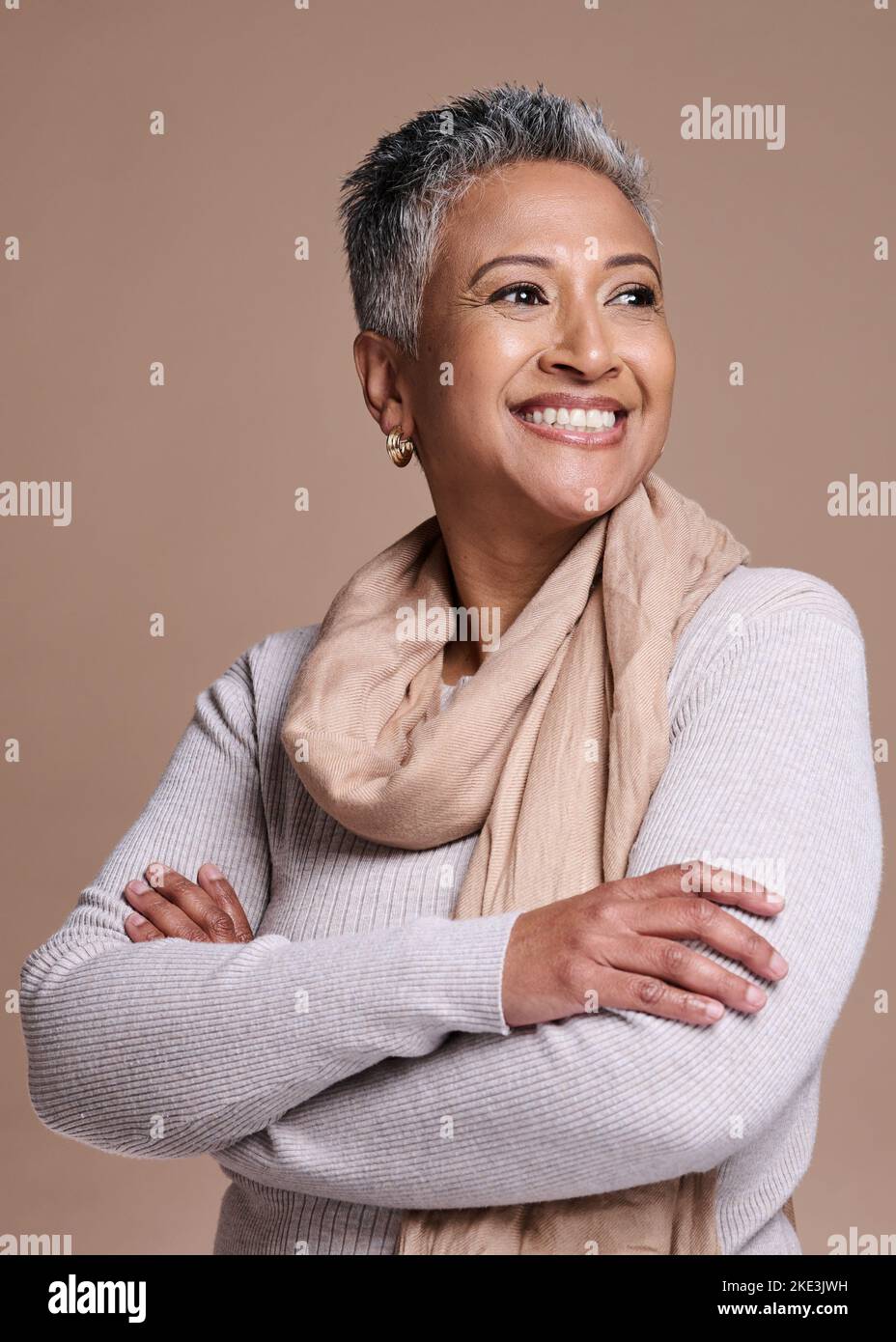 Mode, Denken und Stil mit einer älteren Frau im Studio auf braunem Hintergrund, um eine zeitgenössische Marke zu modellieren. Idee, Lächeln und trendy mit einem reifen Stockfoto