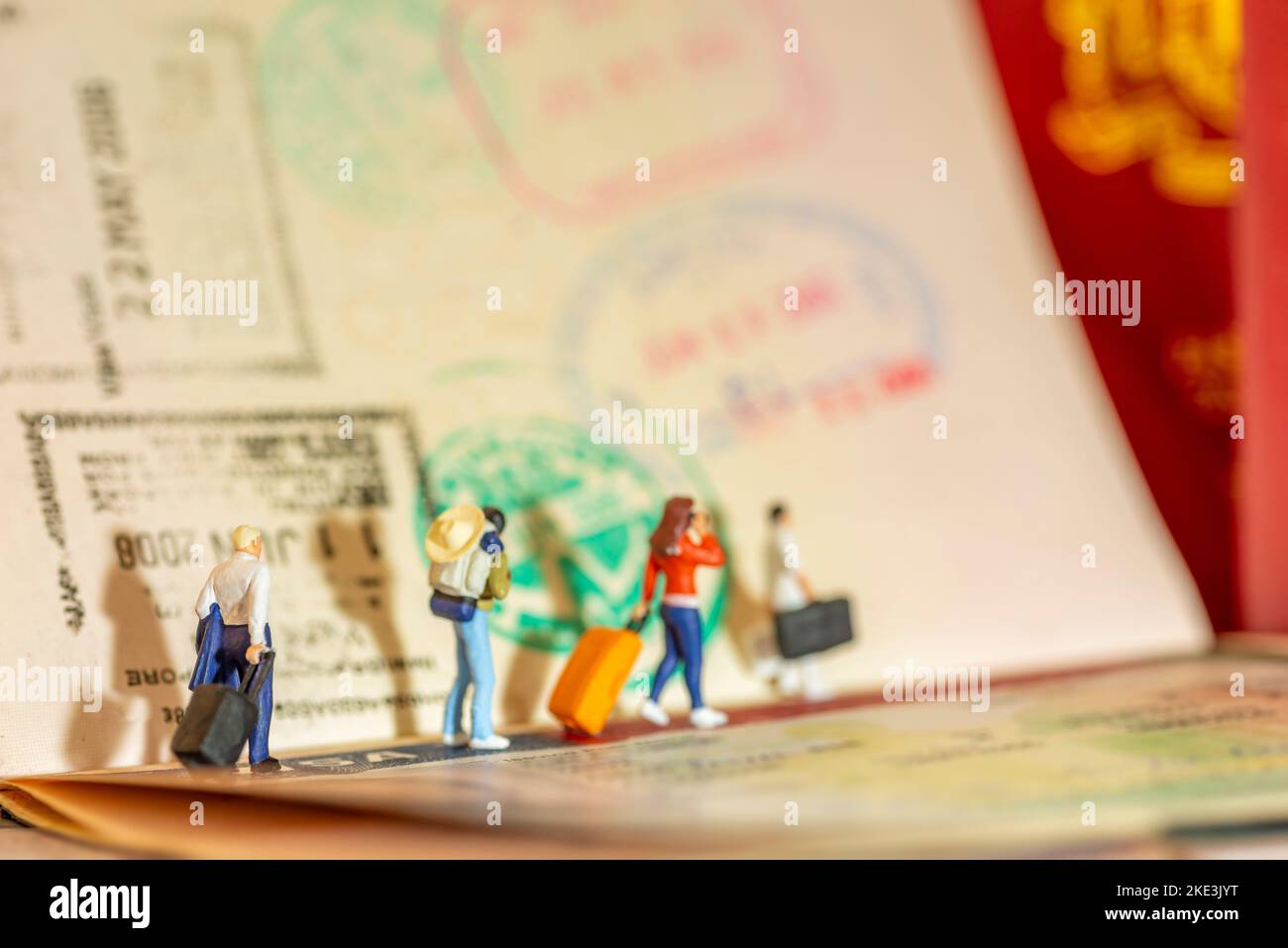 Mini-Spielzeug Konzept Studio-Setup - Expatriate Business Mann zieht ein Gepäck kommt oder verlässt mit Visa-Passstempel als Hintergrund. Seite Stockfoto
