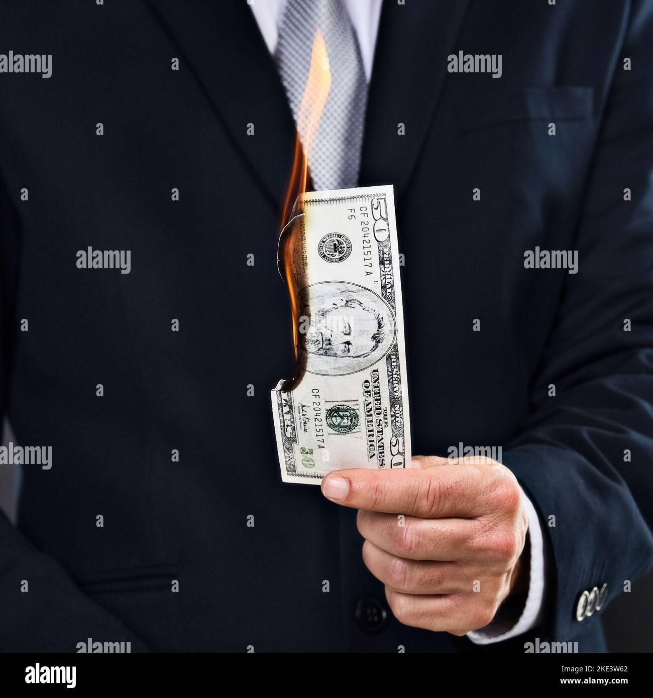 HES hat Geld zum Brennen bekommen. Ein Geschäftsmann mit brennender Banknote. Stockfoto