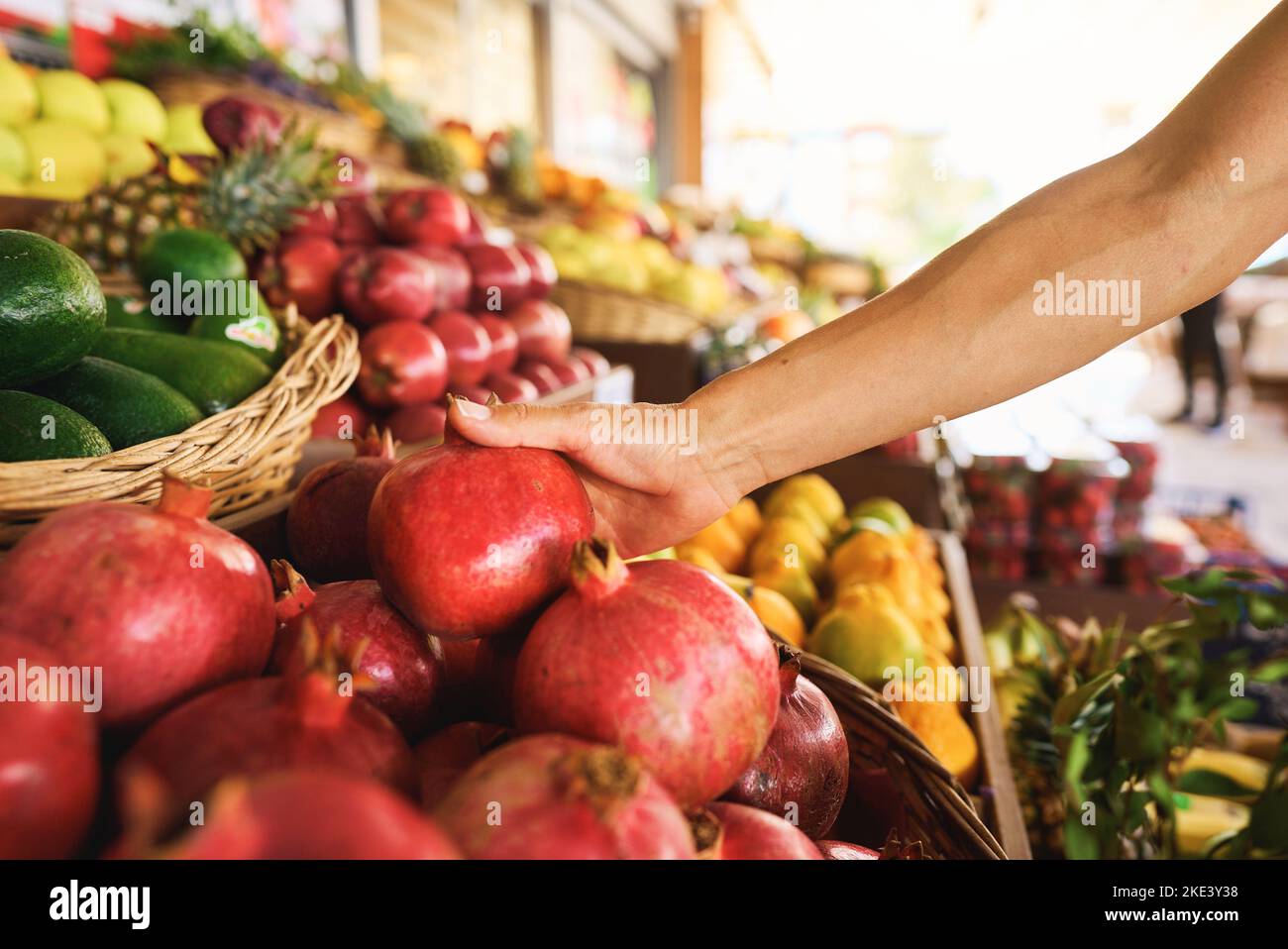 Frau, die unter vielen anderen Granatapfel auswählt, während sie auf dem lokalen Lebensmittelmarkt großartige Lebensmittel einkaufen kann. Stock Foto Stockfoto