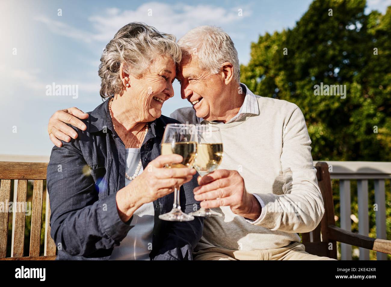 Es gibt noch viele weitere glückliche Tage. Ein glückliches Seniorenpaar, das an einem gemütlichen Nachmittag draußen mit Wein toaste. Stockfoto