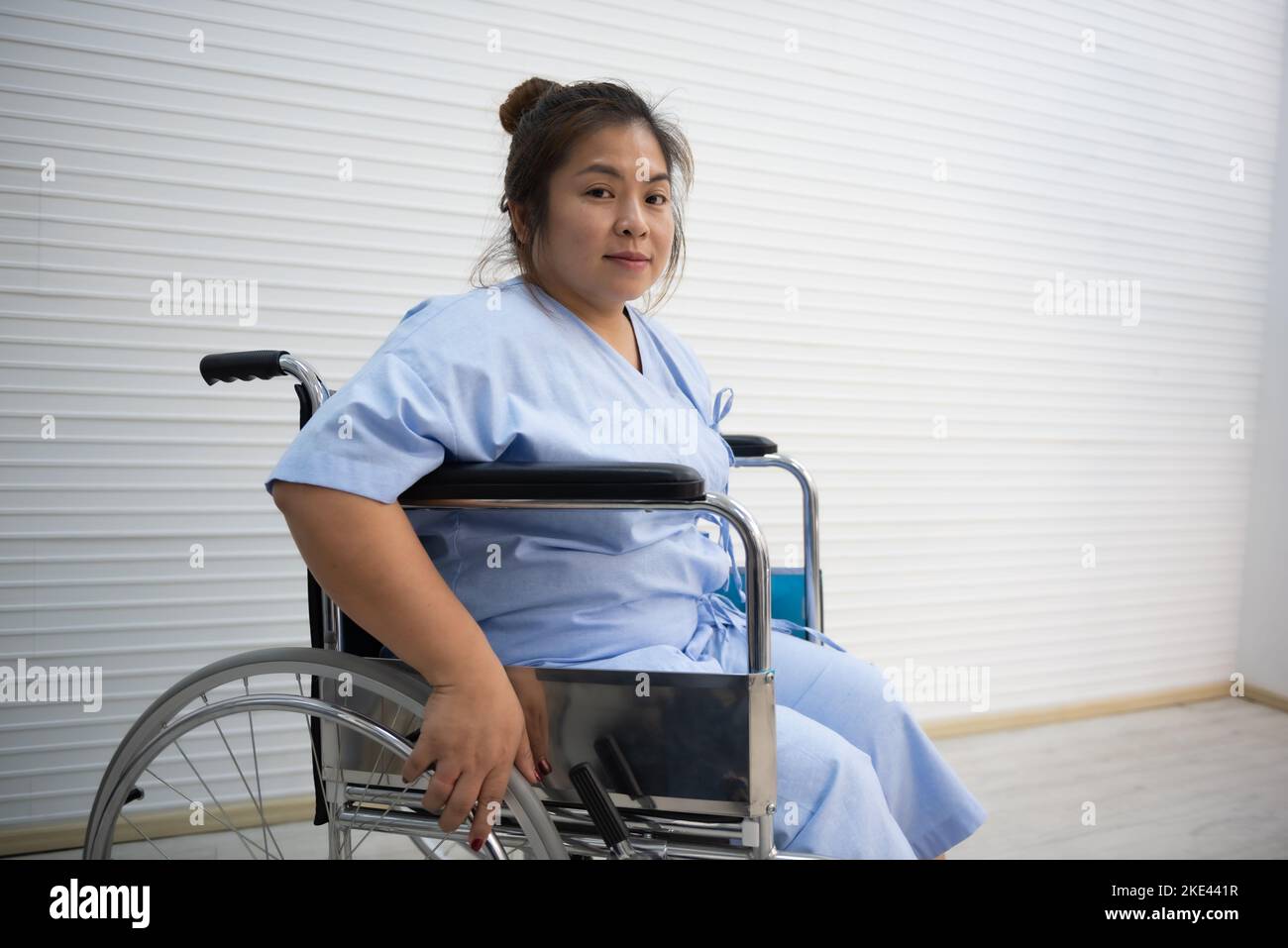 Asiatische fette Frau Patientin sitzt auf einem Rollstuhl, Knieschmerzen, übermäßiges Gewicht, Gesundheitskonzept. Stockfoto