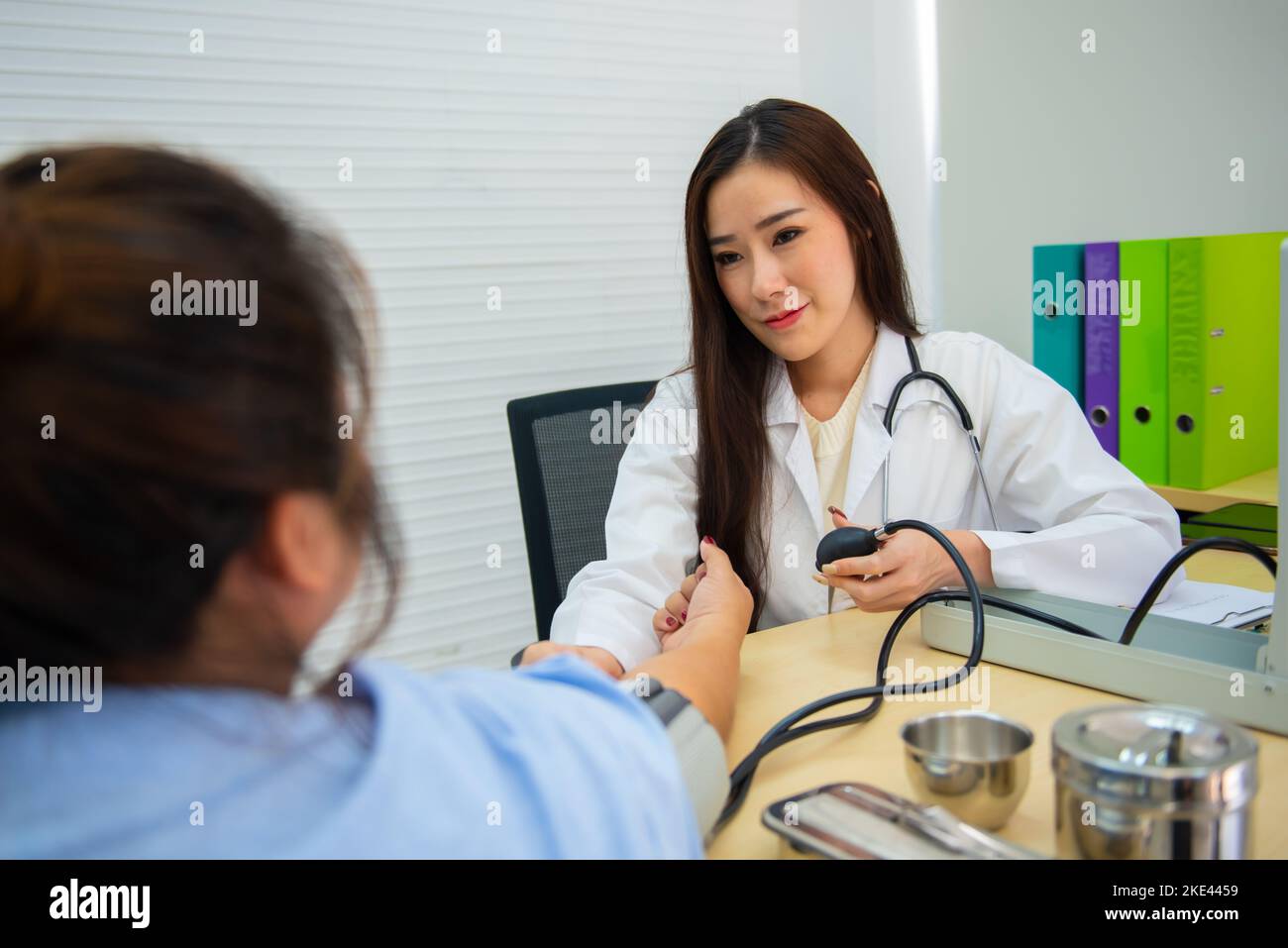 Asiatische Ärztin verwendet Quecksilber-Blutdruck, um den Blutdruck des Patienten zu bestimmen. Stockfoto