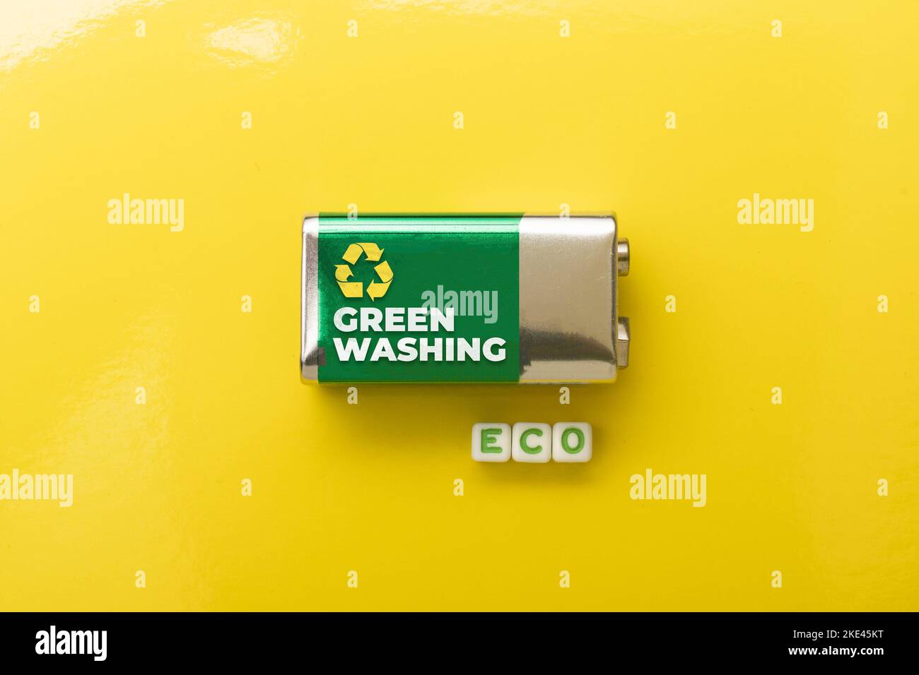 Greenwashing-Konzept: Batterie auf gelbem Hintergrund und sterben das Wort eco Stockfoto