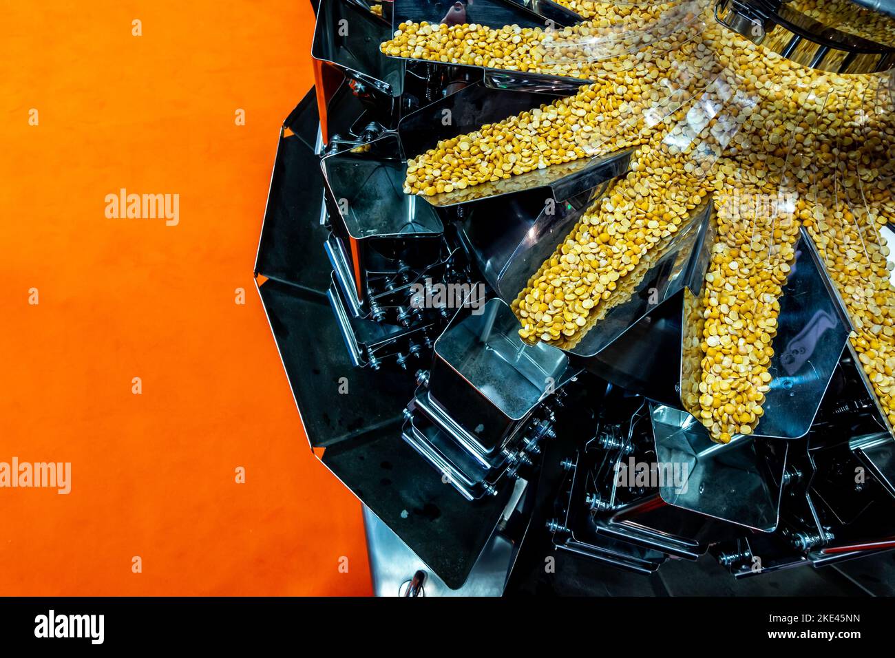 Eine industrielle Mehrkopf-Wägemaschine, die Erbsen-Portionen für die Verpackung vorbereitet. Das Foto wurde unter natürlichen Lichtbedingungen aufgenommen. Stockfoto