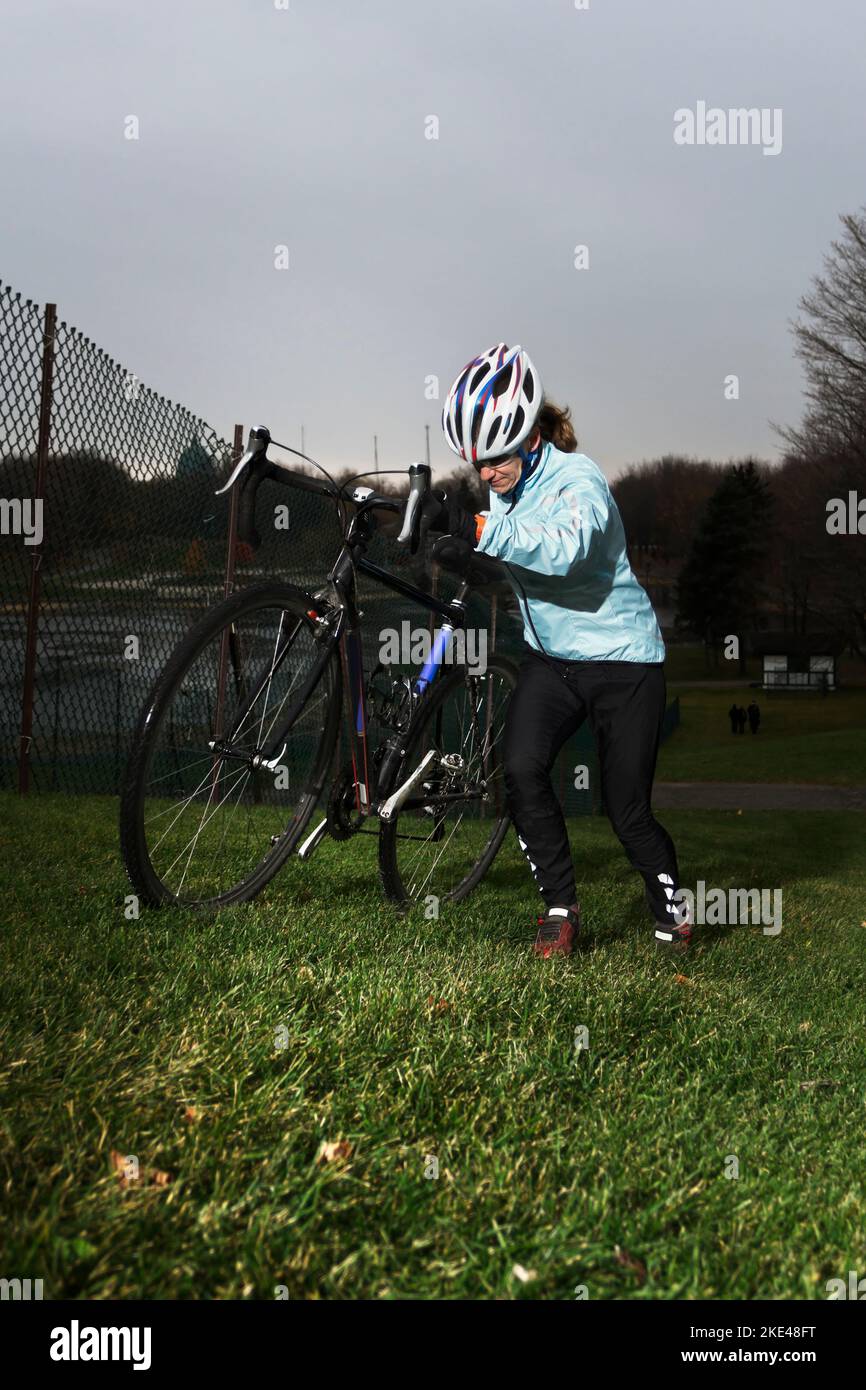 Weibliche Athlet Cyclocross Racer trägt sein Fahrrad einen steilen Hang hinauf. Stockfoto