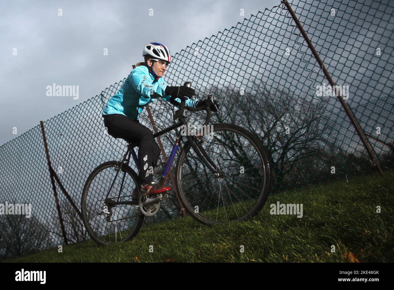 Weibliche Athletin trainiert für ein Herbstrennen an einem kalten bewölkten Tag. Stockfoto