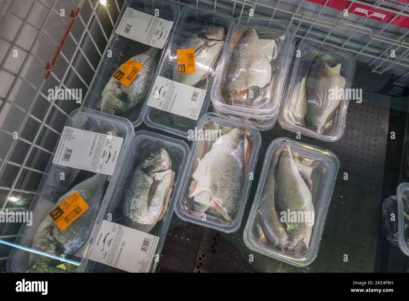 Fossano, Italien - 11. November 2022: Geriebene Seebrasse in Kunststoffverpackungen, die in der Kühltheke eines italienischen Supermarkts verkauft werden Stockfoto