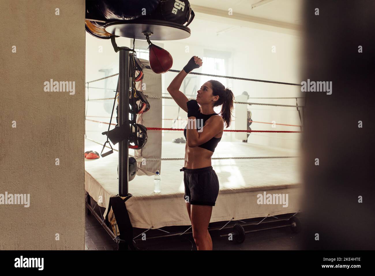 Weibliche Sportlerin trainiert mit einem kleinen Boxsack in einer Boxhalle. Boxerin, die in einem Fitness-Studio trainiert. Stockfoto