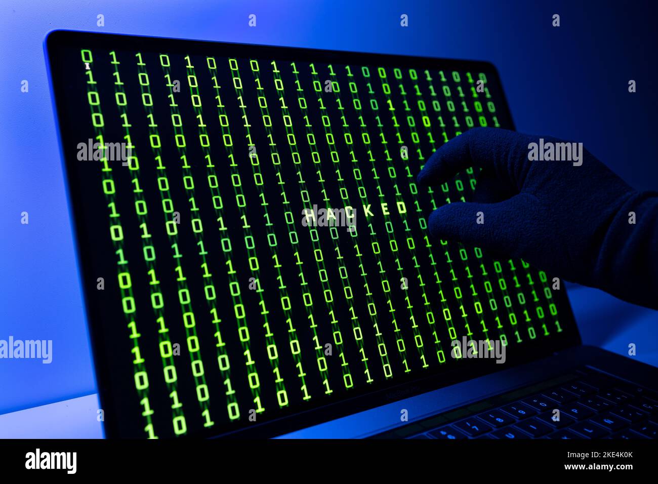 Gehacktes oder gehacktes Computerkonzept. Handschuhen, Binärcode und gehacktes Wort auf Laptop-Computer-Bildschirm Stockfoto