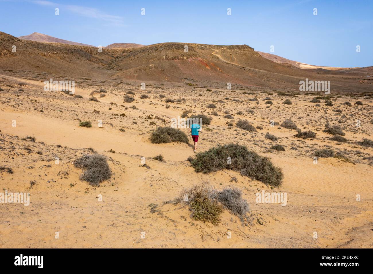 Mann im Urlaub, der einen Spaziergang entlang von Pfaden in vulkanischer Landschaft in der Nähe der Strände von Lanzarote, Kanarische Inseln, Spanien macht. Stockfoto