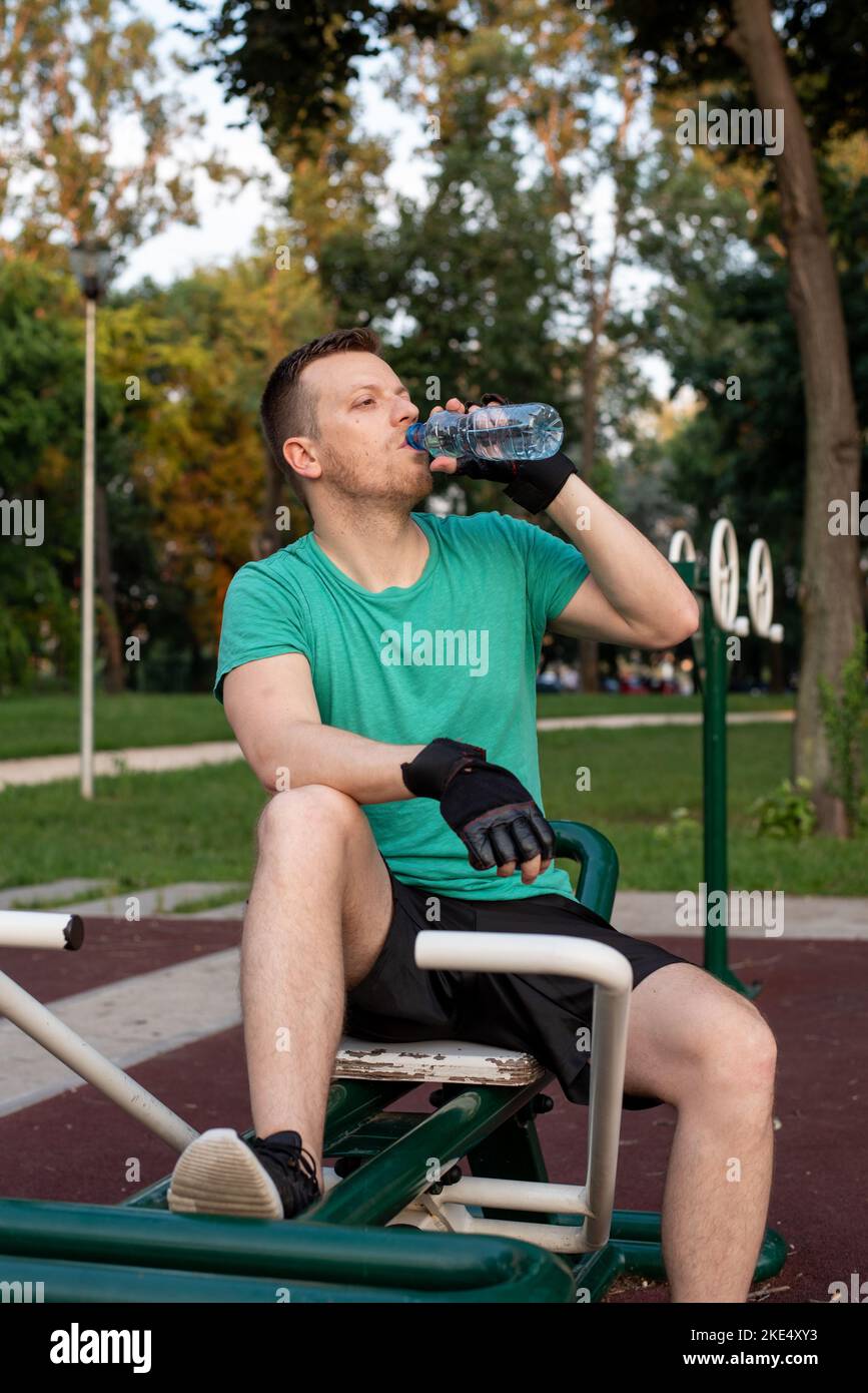 Guy Training in Outdoor-Fitness-Studio auf Rudergerät Stockfoto