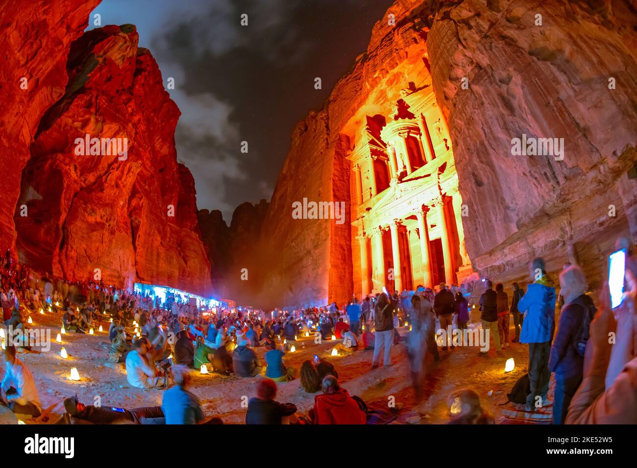 Touristen, die vor der Schatzkammer in Petra Jordan sitzen und nachts von Kerzen erleuchtet werden Stockfoto