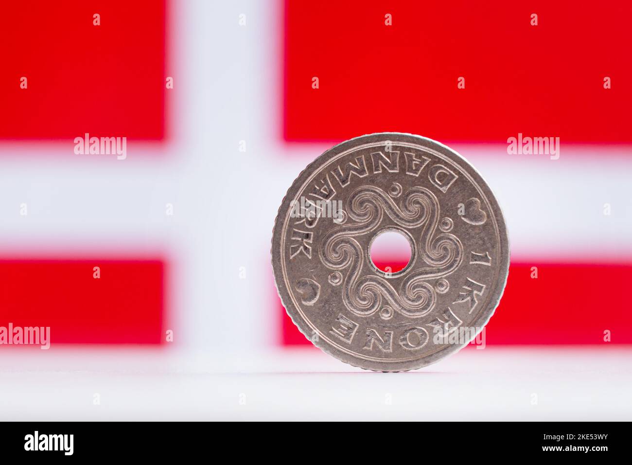 Dänische 1 Kronen mit einer dänischen Flagge im Hintergrund - makroregionaler oberflächlicher Fokus Stockfoto
