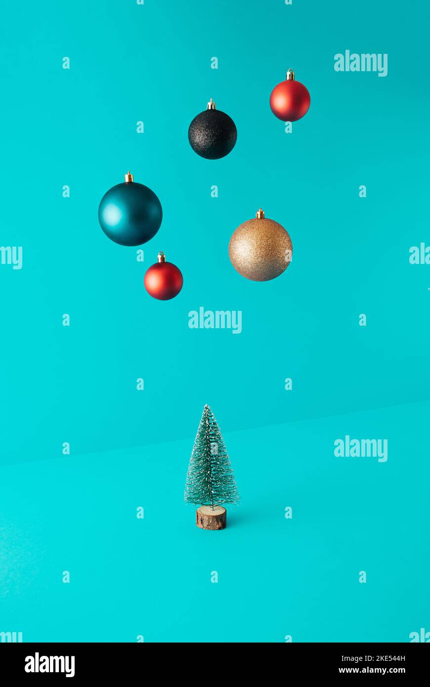 Minimale Komposition mit Weihnachtsbaum und Kugeln in schwebender Farbe auf türkisfarbenem Hintergrund. Konzept für das neue Jahr. Stockfoto