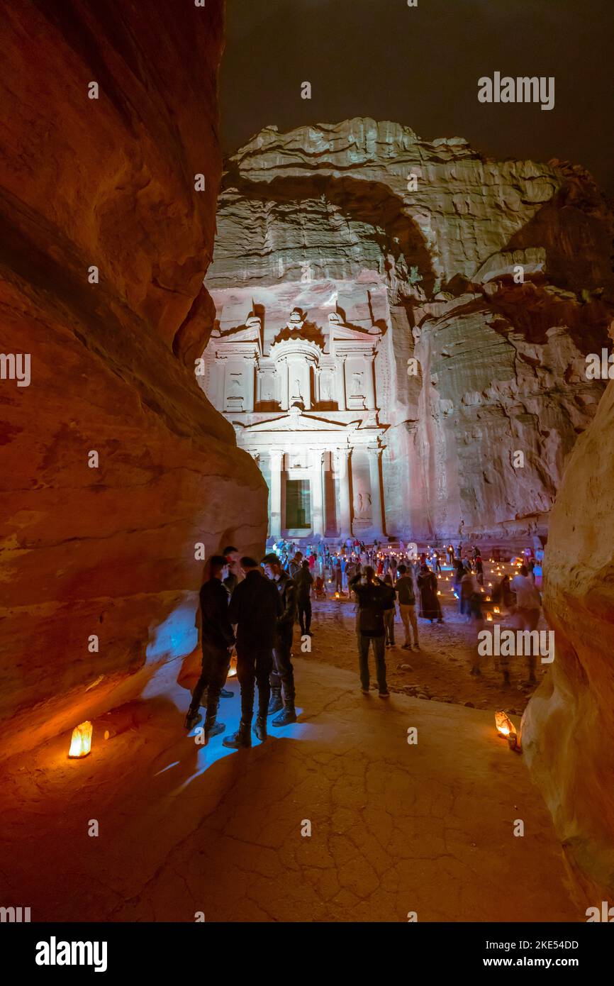 Touristen, die vor der Schatzkammer in Petra Jordan sitzen und nachts von Kerzen erleuchtet werden Stockfoto