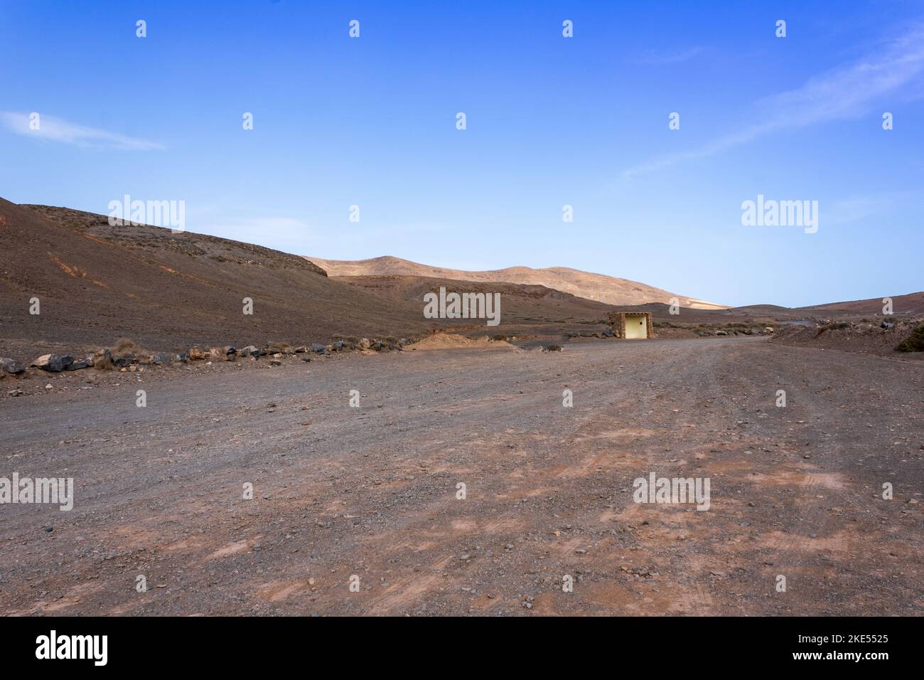 Einsame Wüstenstraße durch eine dürre Landschaft windet sich am Horizont in Richtung vulkanischer Berge, nahe Playa Mujeres und der Papagayo-Küste, Lanzarote, Ca Stockfoto