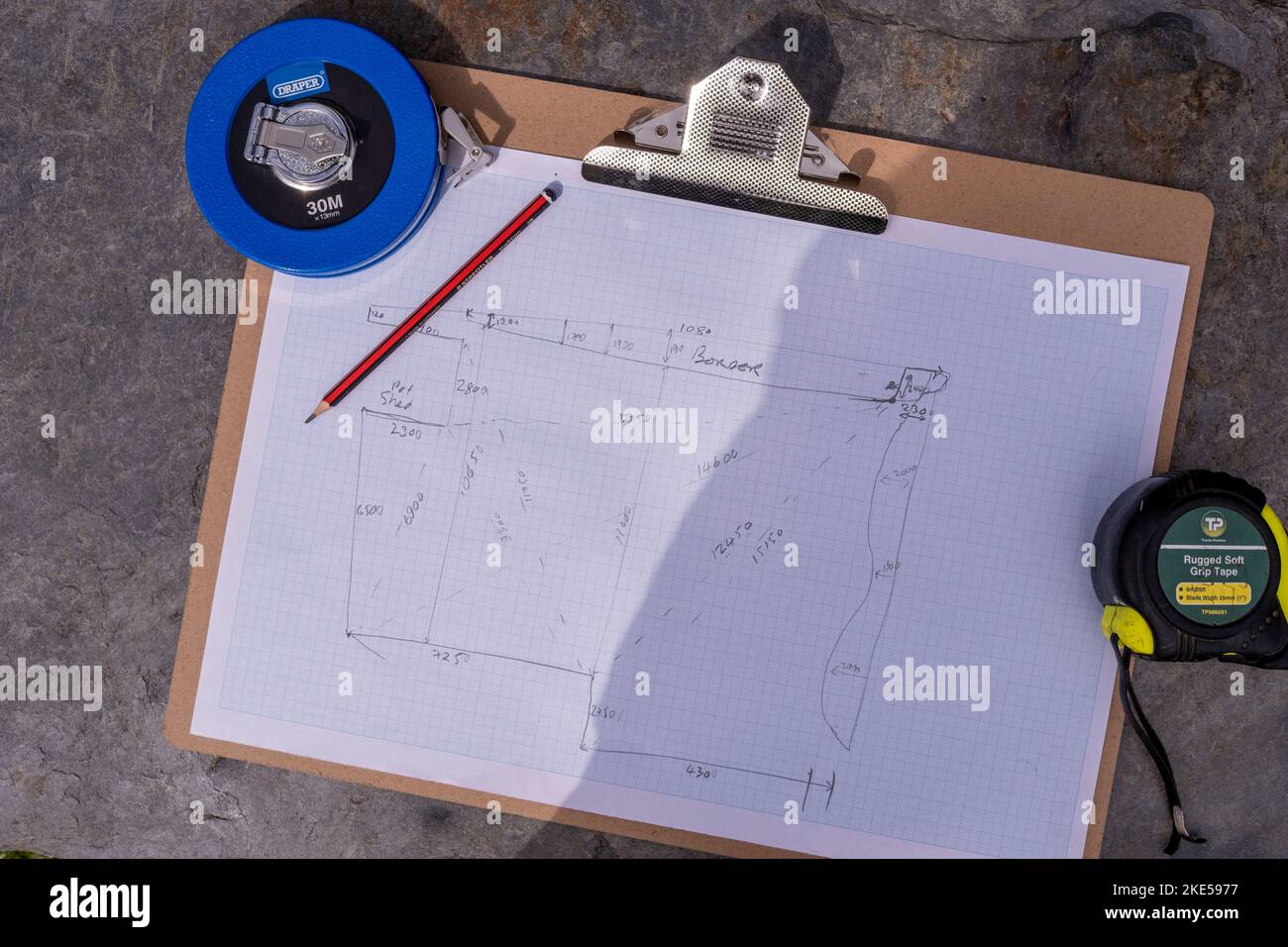 Einen Plan für einen Garten mit Maßband, Zeichenpapier und einem Bleistift erstellen Stockfoto