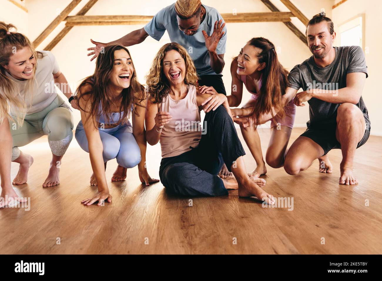 Eine Gruppe glücklicher Fitnessfreunde, die in einem Yoga-Studio lachen und Spaß haben. Multikulturelle Menschen, die eine Pause von einer Yoga-Sitzung machen. Sportliche Menschen sind dabei Stockfoto