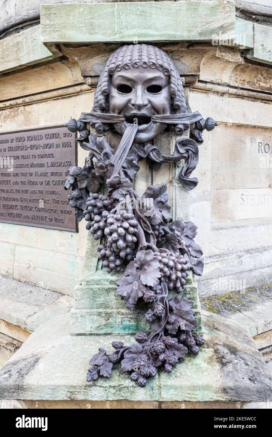 Nahaufnahme einer von vier Bronzemasken mit Efeu- und Zypressenblumen auf dem Gower Memorial zu William Shakespeare in Bancroft Gardens, Stratford upon Avo Stockfoto