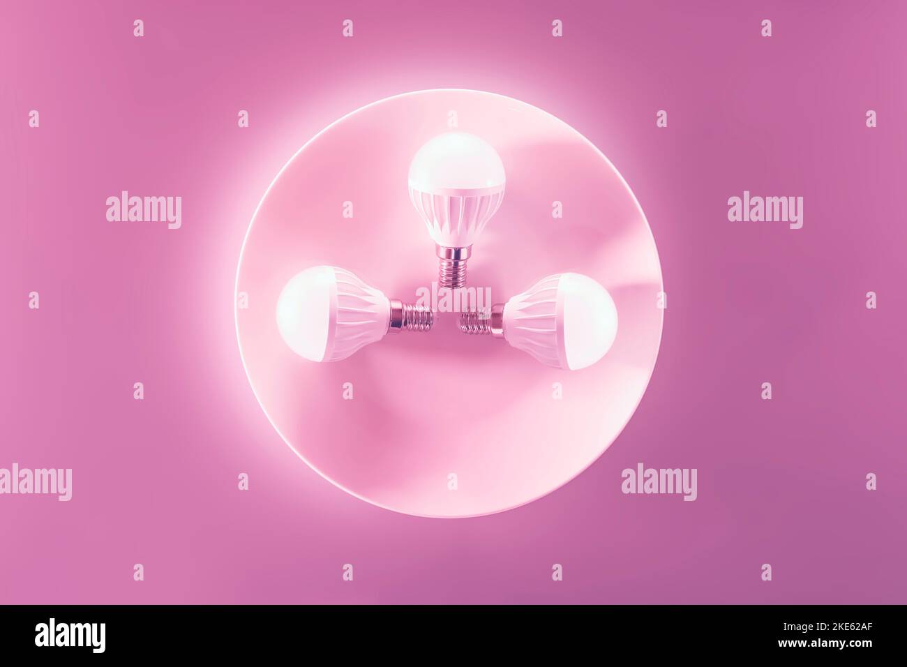 Drei leuchtende LED-Lichter auf einem weißen Teller, rosa Hintergrund. Energiesparende Technologie. Stockfoto