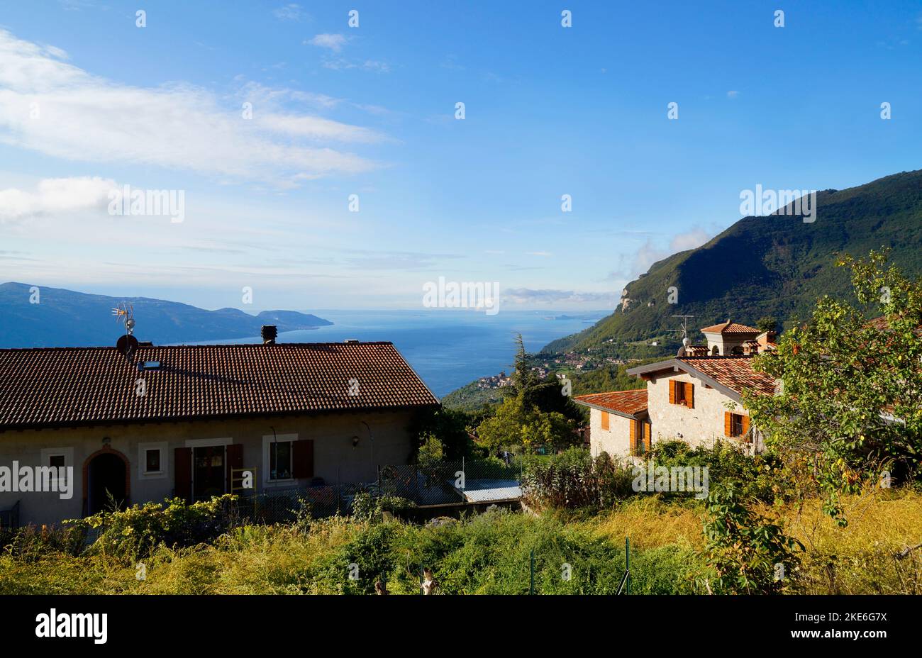 Sonnendurchflutete mediterrane Landschaft mit einem italienischen Dorf mit Blick auf den riesigen blauen Gardasee und die italienischen Alpen in der Nähe von Tignale, Lombardei, Italien Stockfoto
