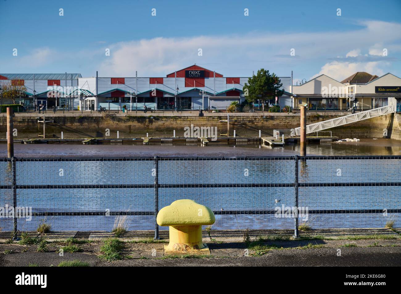Leuchtend gelber Poller, der sich gegen den Yachthafen und das Affinity-Einkaufszentrum Fleetwood befindet Stockfoto