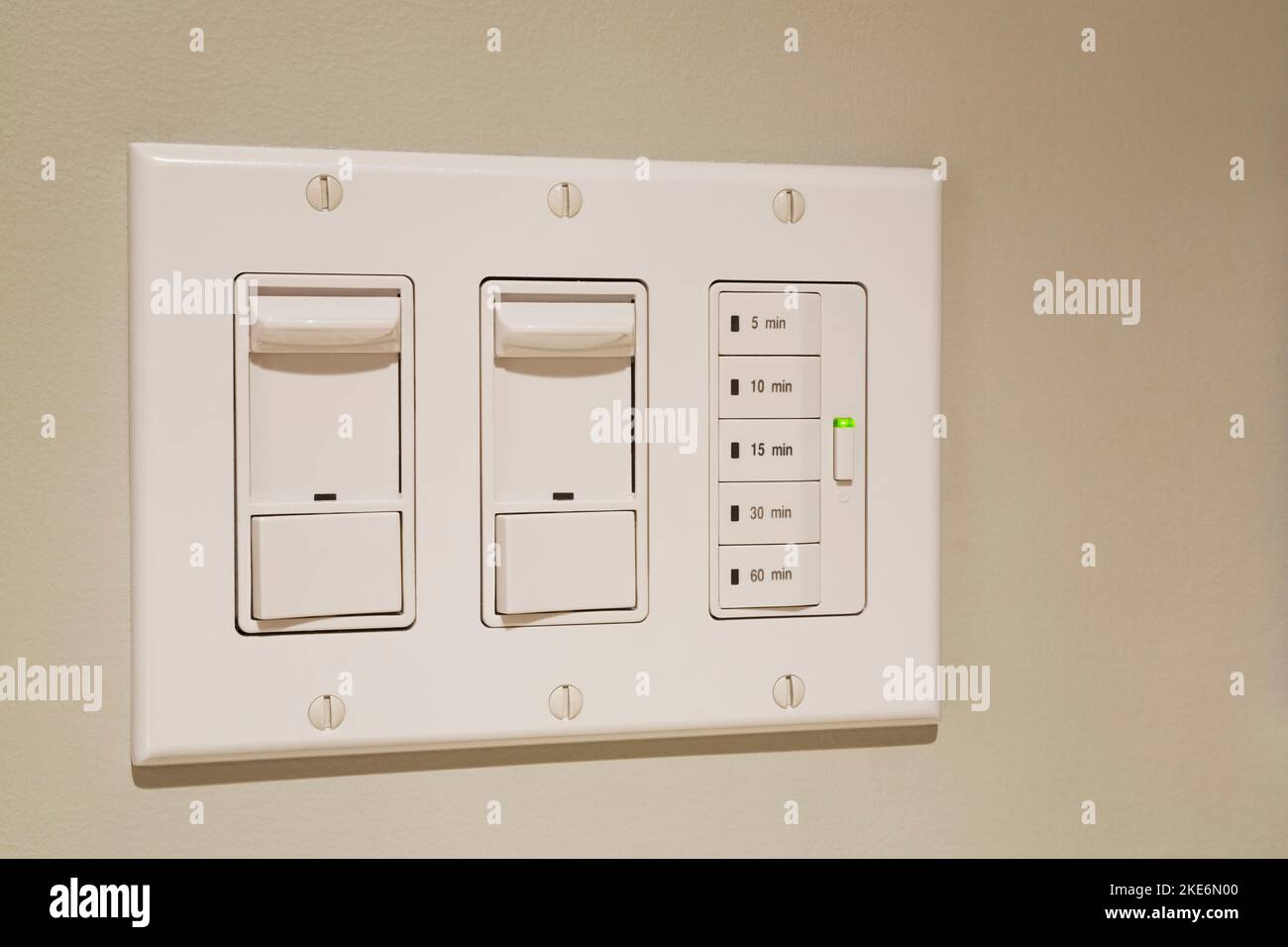 Wandschalter für Glühlampen-Dimmer-Beleuchtung und Abluftventilator-Timer an der Wand in der Waschküche und im Badezimmer in einem Wohnheim. Stockfoto