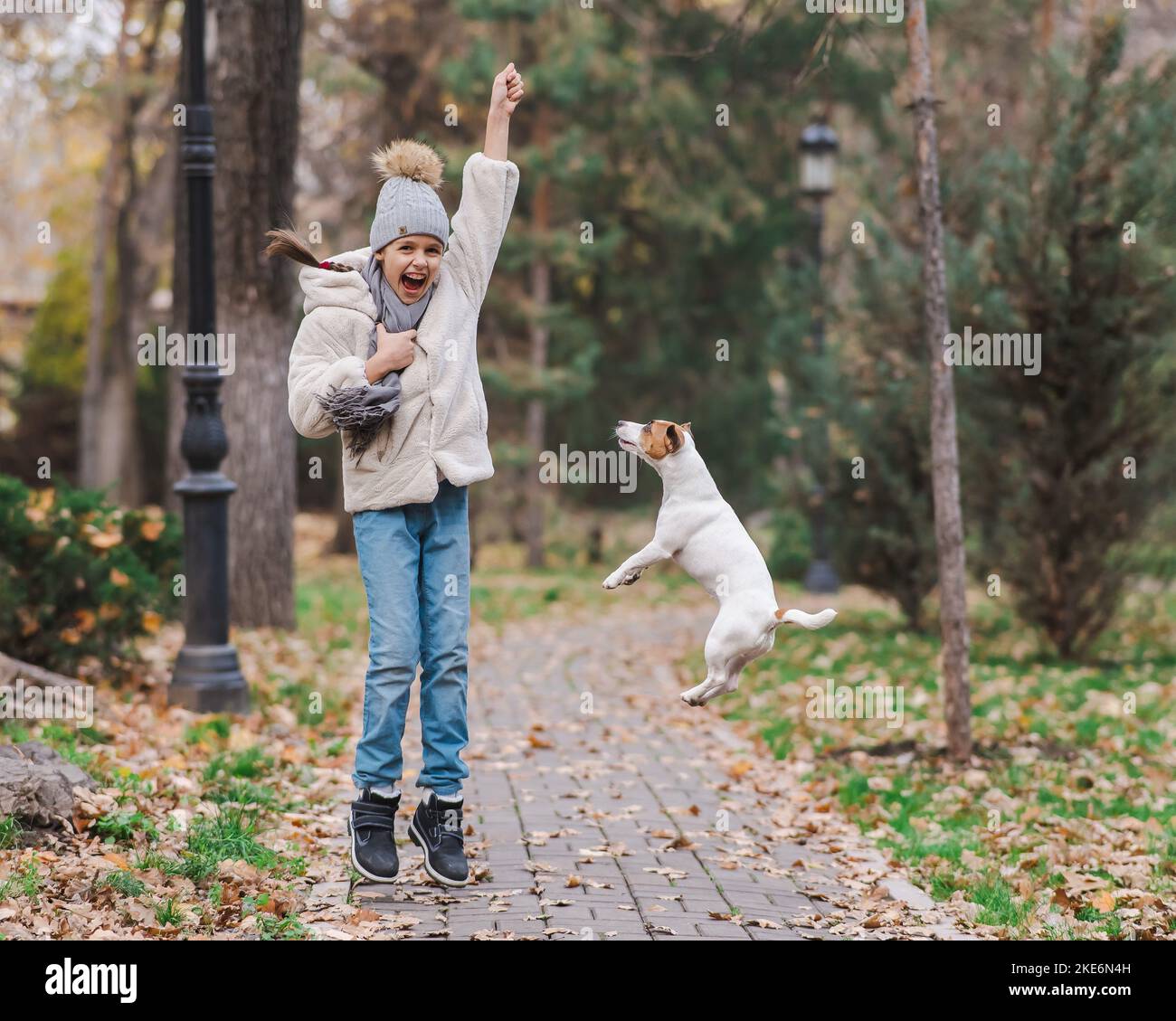 Kaukasisches Mädchen spielt mit einem Hund für einen Spaziergang im Herbstpark. Stockfoto
