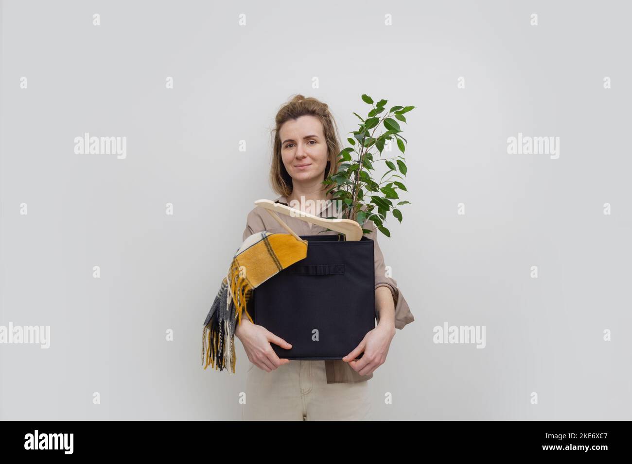 Glückliche entlassene Frau, die mit einer Kiste voller Sachen auszieht. Stockfoto