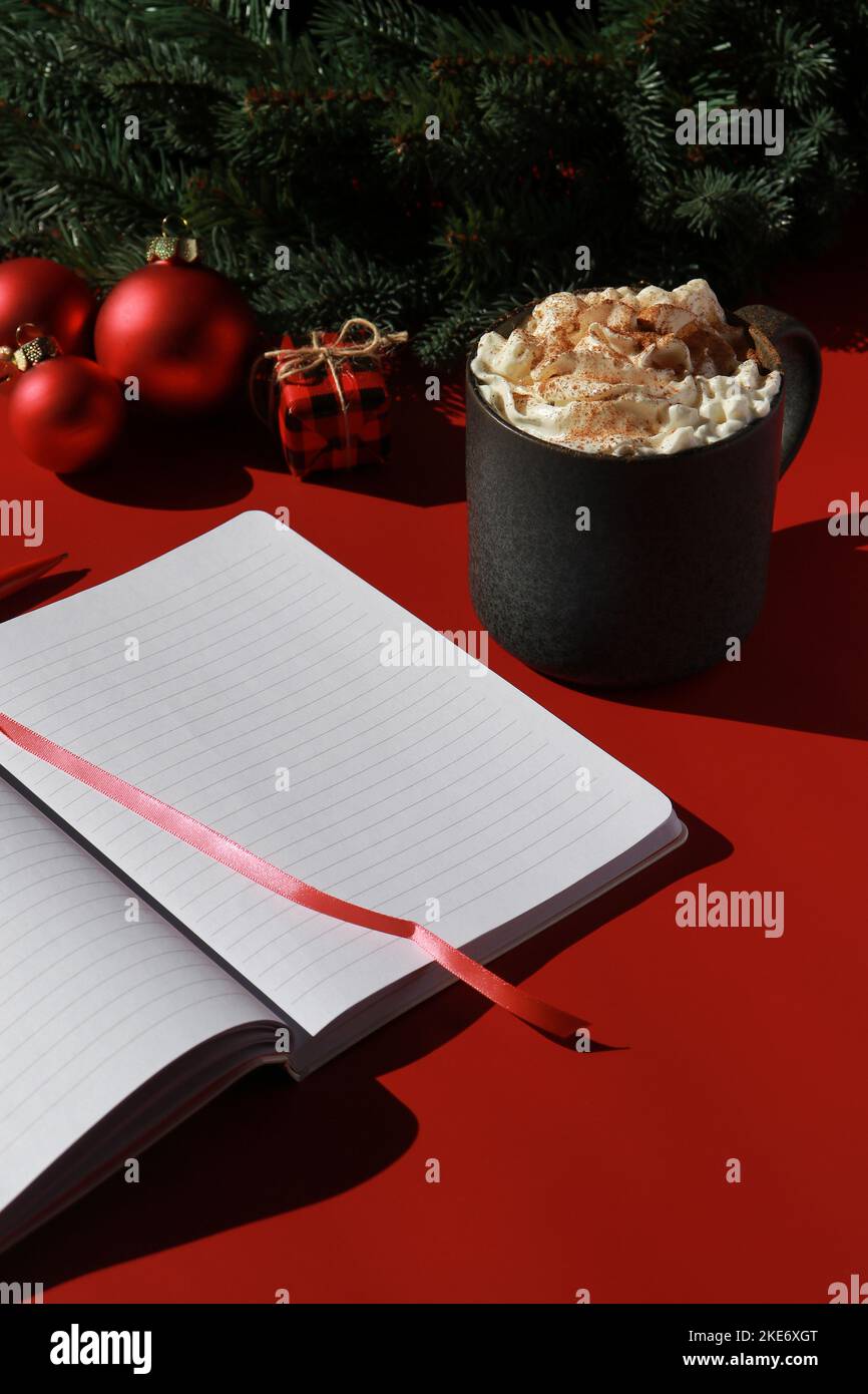 Rote Weihnachtskomposition mit heißer Schokolade und Notizbuch für Wunschliste Stockfoto